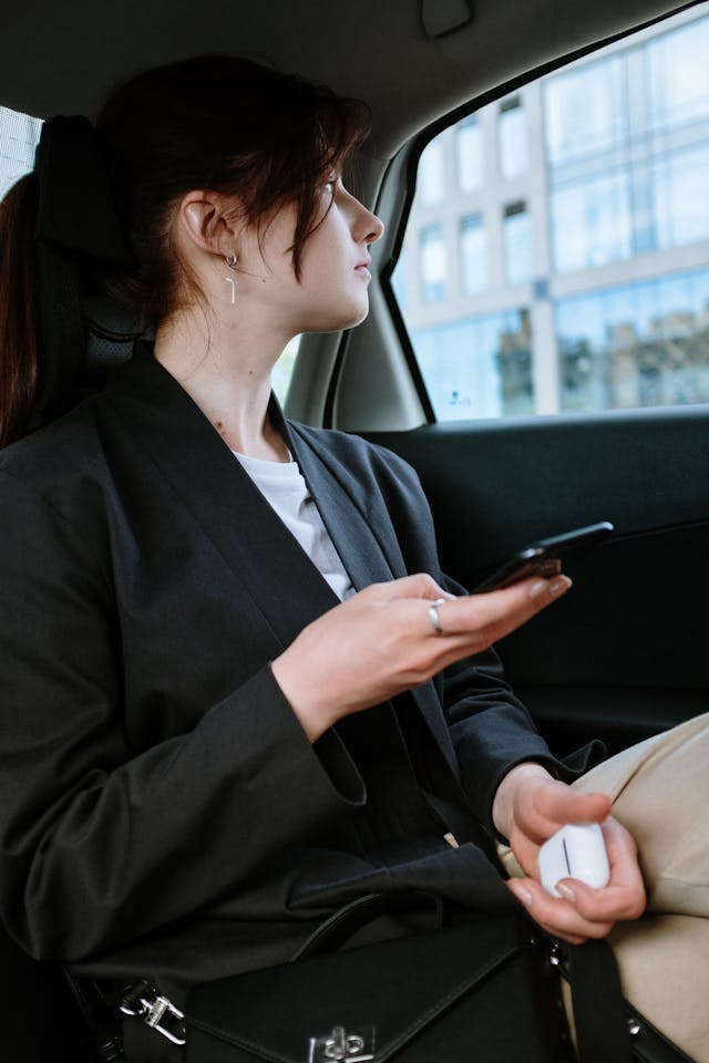 Passenger using a smartphone inside a taxi in Australia, depicting a comfortable and modern ride experience.