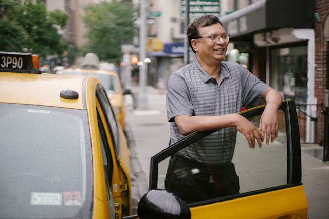 Friendly taxi driver standing beside a taxi in Australia, ready to assist you.